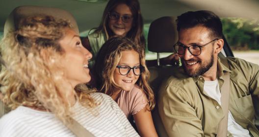 Семья с двумя детьми в комнате, все смеются и хорошо проводят время вместе. 