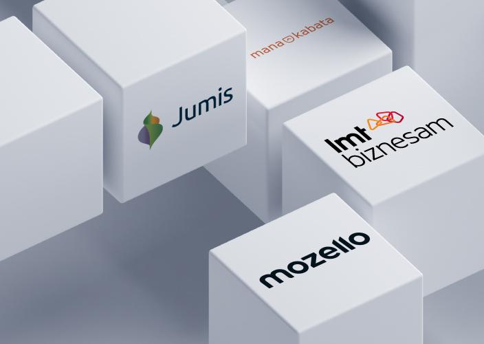 Balti kubi, uz kuriem redzami Jumis, LMT biznesam, Mozello un MANAKABATA logotipi.