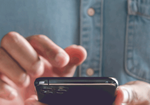 Woman holding a phone in hands, typing on it.