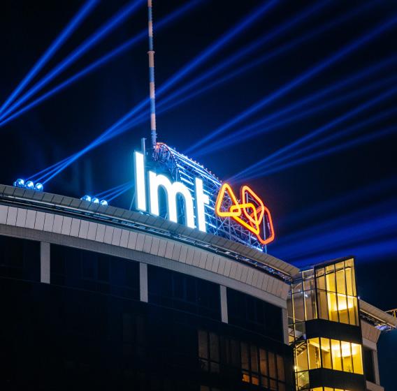 Здание с подсвеченным логотипом LMT ночью.