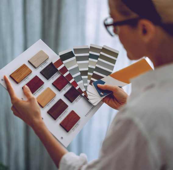 A woman is looking at floor parquet and wall paint sample palettes to plan home improvements. 